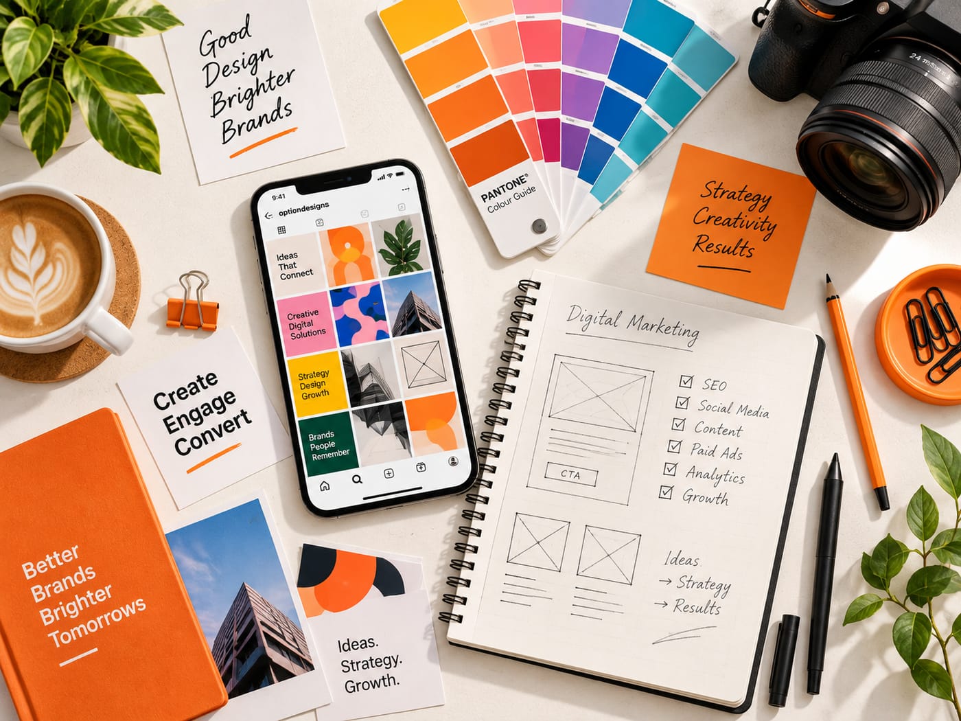 Flat lay of a phone with social media designs, colour swatches, a camera and a sketchbook with digital marketing wireframes